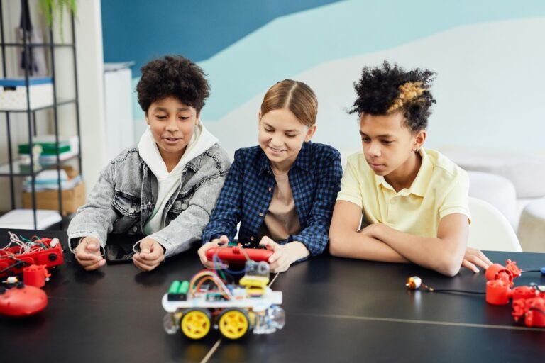 Teens exploring and building robotics at a table indoors, showcasing teamwork and technology skills.